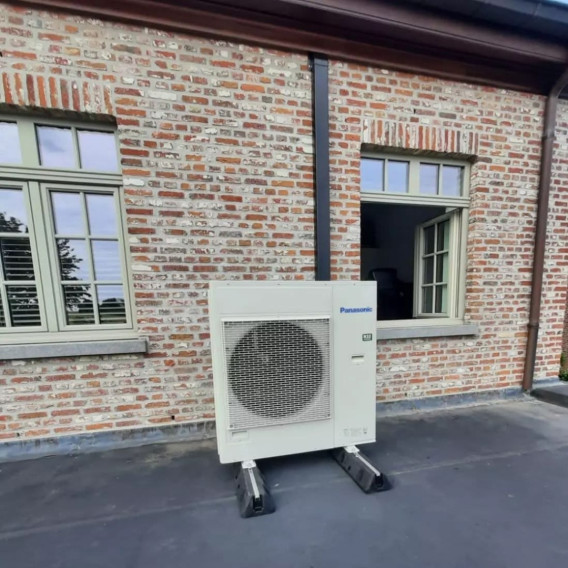 Panasonic buitenunit van een warmtepomp tegen een gevel in rustieke baksteen, Ternat
