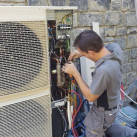 Technieker van Elektro Moerenhout aan het werk in een buitenunit van een warmtepomp